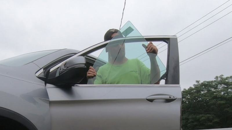 Joe from Clancy's Auto Glass lowering a new side window into the front door of an SUV after replacing broken door glass